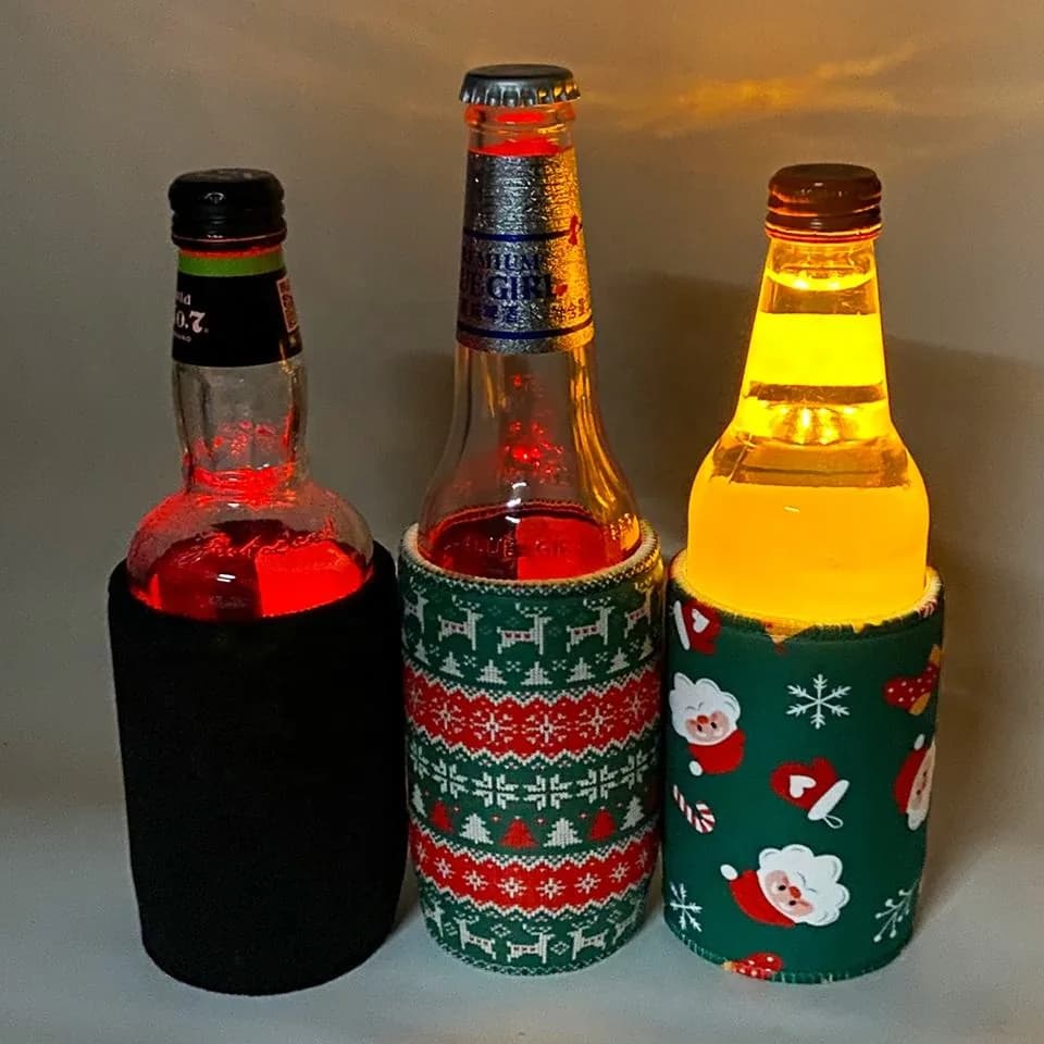 Three glass bottles lit from their neoprene LED sleeves in a dark setting