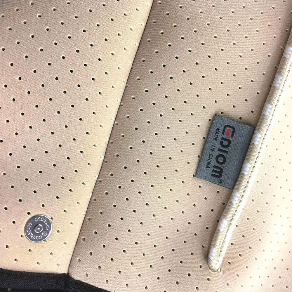 Close-up of tote perforations, side snap, rope and woven label